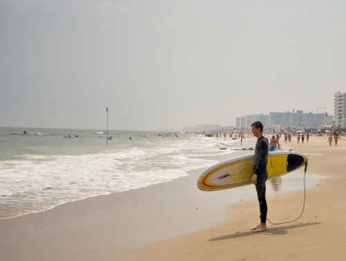 A surfer holds his surf board at Rockaway Beach in Queens, New York
