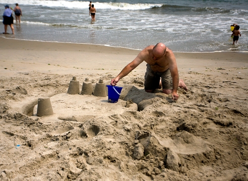 A man builds a sand castle along Rockaway Beach in Queens, New York.